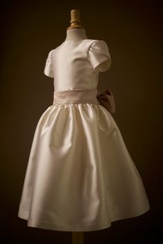 A simple and elegant flower girl dress for girls. Handmade and made-to-measure by professional dressmaker, Mary Grace Godfrey, in the Anagrassia Atelier. See the dress in a real wedding here: Matching Flower Girl & Junior Bridesmaid Dresses White Silk Wool Flower Girl Dress Details: Bodice made with a stunning diamond white* silk wool. Bodice lined with silk charmeuse Petal sleeves made with silk wool Full silk wool gathered skirt Back Invisible Zipper Big Wide Silk Wool Sash (Available colors: Elegant Fitted Cream First Communion Dress, Elegant Fitted First Communion Dress For Formal Occasions, Elegant Fitted First Communion Dress, Elegant Ball Gown For Confirmation, Elegant Gown With Fitted Bodice For First Communion, Elegant First Communion Gown With Fitted Bodice, Classic Cream Dress For Confirmation, Elegant Cream First Communion Dress, Elegant Fitted First Communion Dress With Satin Bow