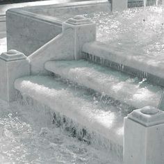 a fountain with water running down it and steps leading up to the bottom that are covered in ice