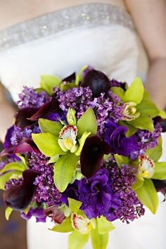 the bride's bouquet is adorned with purple orchids and green calla lilies