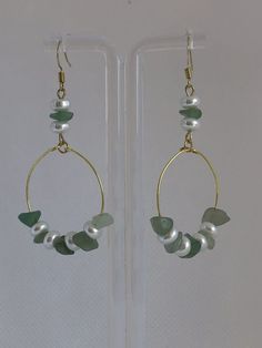 a pair of gold hoops with pearls and green glass beads on each earring