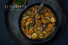 a bowl of stew with mushrooms, carrots and celery next to a spoon