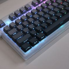 a close up of a computer keyboard on a white surface with blue and red lights