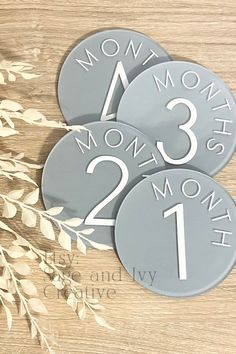 three round metal signs with numbers on them sitting on top of a wooden table next to flowers