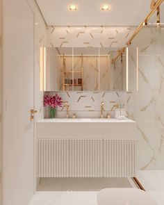 a white bathroom with gold fixtures and marble counter tops, along with a large mirror on the wall