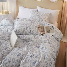 an open laptop computer sitting on top of a bed covered in blue and white sheets