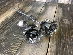 two metal flowers sitting on top of a wooden table