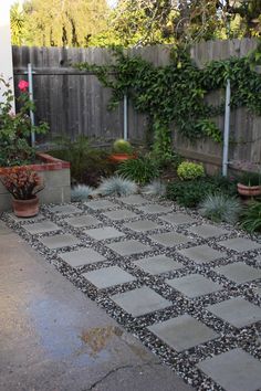 an outdoor patio area with potted plants and graveled walkway leading to a wooden fence