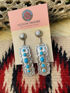 New without tags BRAND : Nizhoni Traders LLC ETHNIC & REGIONAL STYLE : Native American JEWELRY TYPE : Earrings METAL : Sterling Silver TRIBAL AFFILIATION : Navajo MAIN STONE : Turquoise Lovely Navajo Turquoise and Sterling Silver dangle earrings. Measure 2 7/8 inches long and 3/4 of an inch wide. Great pair of earrings! Stamped Sterling and signed by the artist. Thank you for checking out my store. Please contact me with any questions. Exported By exportyourstore.com