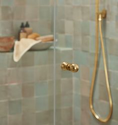 a shower with a glass door and gold fixtures in the shower head is next to a towel rack