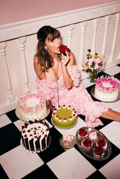 a woman in pink dress sitting on floor next to cake