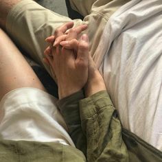 two people holding hands while laying in bed