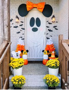 mickey mouse decorations on the front steps of a house with pumpkins and yellow flowers