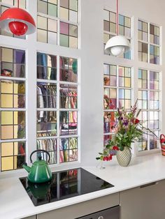 a kitchen with white counter tops and lots of colorful glass blocks on the wall behind it