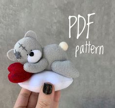 a hand holding a gray teddy bear with a heart on it's pillow that says pdf pattern