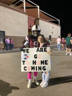 two people in football uniforms holding a sign that says we are going to home coming