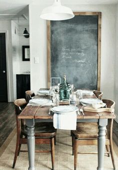 a dining room table is set with place settings for six people and the chalkboard in the background has writing on it