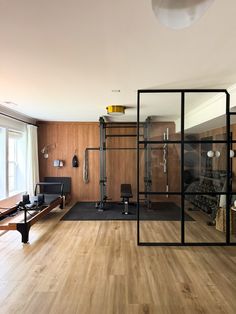 a home gym with hard wood flooring and black glass partitions to the wall