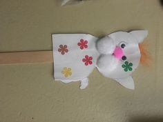 a white stuffed animal with flowers on it's head is hanging from a wall