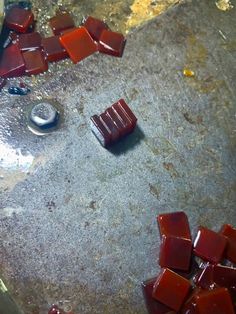 red pieces of glass sitting on top of a cement floor next to a metal object