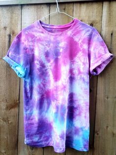 a purple and blue tie dye shirt hanging on a wooden fence