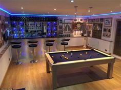 a pool table in the middle of a room with bar stools and pictures on the wall