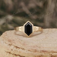 a gold ring with a black stone in the center on top of a large rock