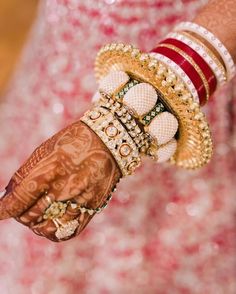 a woman's hand with bracelets and rings on it