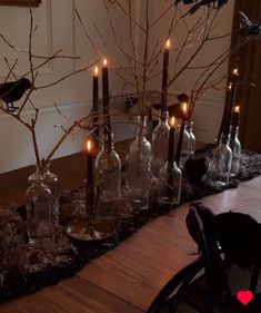 the table is set up with candles and glass bottles for halloween decorations, as well as birds on branches