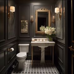 a white toilet sitting next to a sink in a bathroom under a mirror and lights