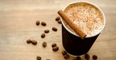 there is a cup of coffee with cinnamon on the table next to some coffee beans