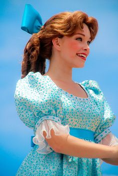 a woman in a blue dress is holding a frisbee