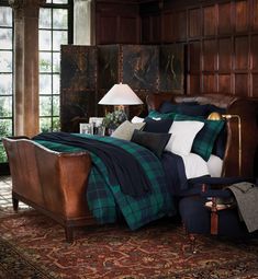 a bed in a room with wooden paneling and plaid comforter on the bed