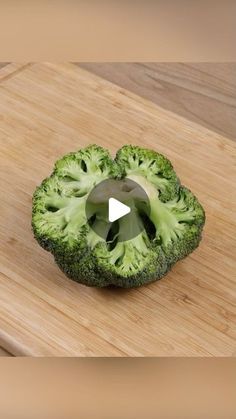 a piece of broccoli sitting on top of a wooden cutting board