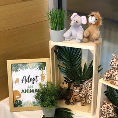 two stuffed animals sitting on top of wooden shelves next to plants and a sign that says adopt an animal