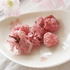 small pieces of food on a white plate with pink flowers in the backgroud