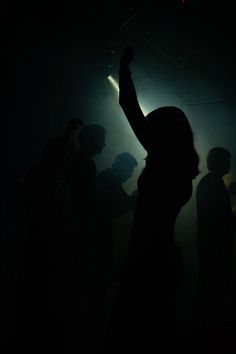 a person standing in the dark with their arms up