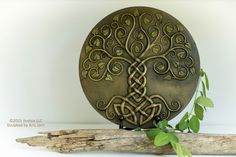 a decorative metal object sitting on top of a piece of driftwood next to a plant