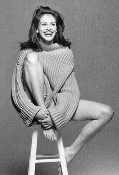 a black and white photo of a woman sitting on a stool