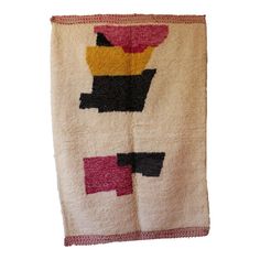 a white towel with black, yellow, and pink designs on the front is hanging from a hook