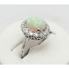 an opalite and diamond ring on a white cloth with the center stone surrounded by diamonds