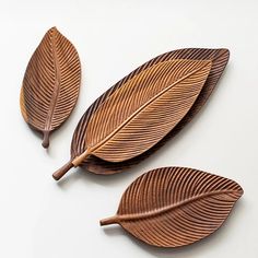 three wooden leaves on a white surface