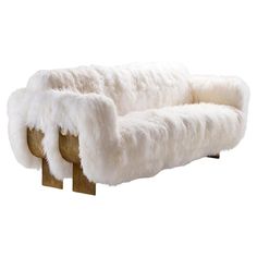 a white fur couch sitting on top of wooden legs