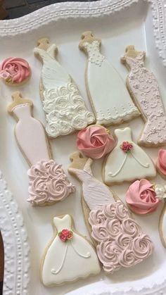 decorated cookies in the shape of wedding gowns and dresses on a white platter