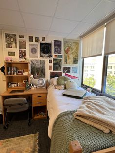 a bed sitting in a bedroom next to a window with lots of pictures on the wall