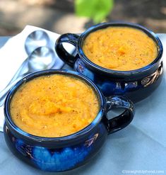 two blue mugs filled with soup sitting on top of a table