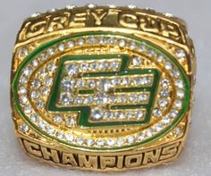 a green and gold ring with the word champion on it's center surrounded by small white diamonds