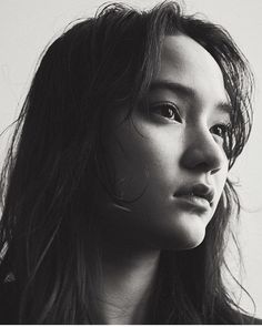 a black and white photo of a woman with long hair looking off to the side