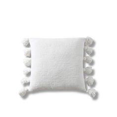 a white pillow with pom - poms on the front and back of it