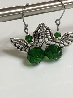 "Small angel earrings 1.25\" From hook to bottom, it dangle 1\" long, 8x10mm emerald green faceted crystal glass silver metals wings nickel and lead free, stainless steel fish hook Hand made jewelry. All purchase will arrive in gifts boxes. Thanks for stopping by!" Green Dangle Crystal Earrings, Green Crystal Earrings For Jewelry Making, Nickel-free Green Sterling Silver Crystal Earrings, Nickel-free Green Crystal Earrings In Sterling Silver, Nickel-free Green Crystal Jewelry, Silver Crystal Earrings For May Birthstone Gift, Nickel-free Green Drop Crystal Earrings, Gifts Boxes, Small Angel