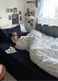 there is a stuffed bear sitting on the bed in this room with blue and white sheets